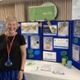 A member of staff at Velindre Cancer Centre is stood next to a display.