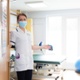 A clinician stands with open arms in the doorway of a hospital room.