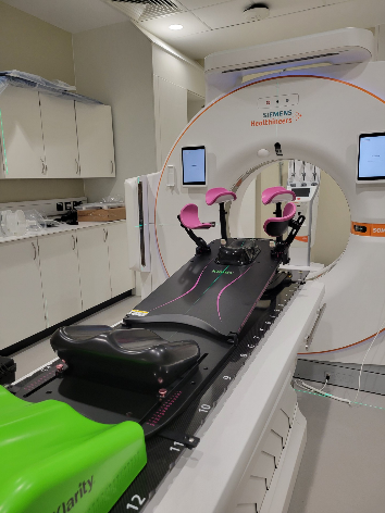 An empty stretcher next to a radiotherapy machine.