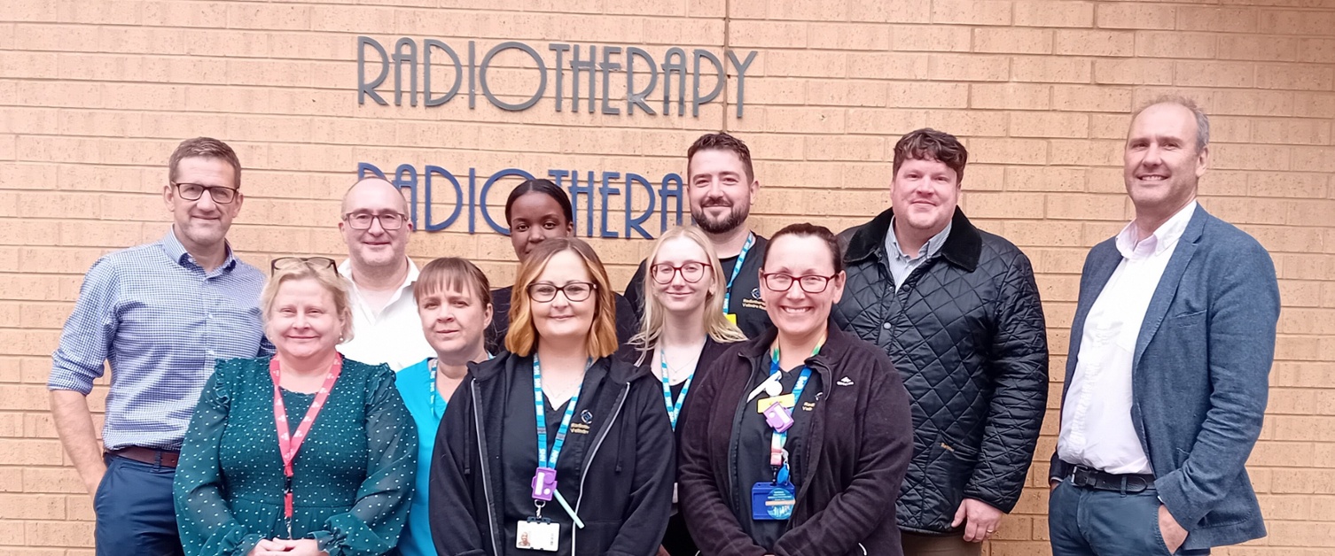 Group photo of the people named in caption standing in front of Radiotherapy building