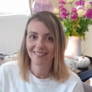 head and shoulders picture of Bethan Thomas in her living room with flowers behind her