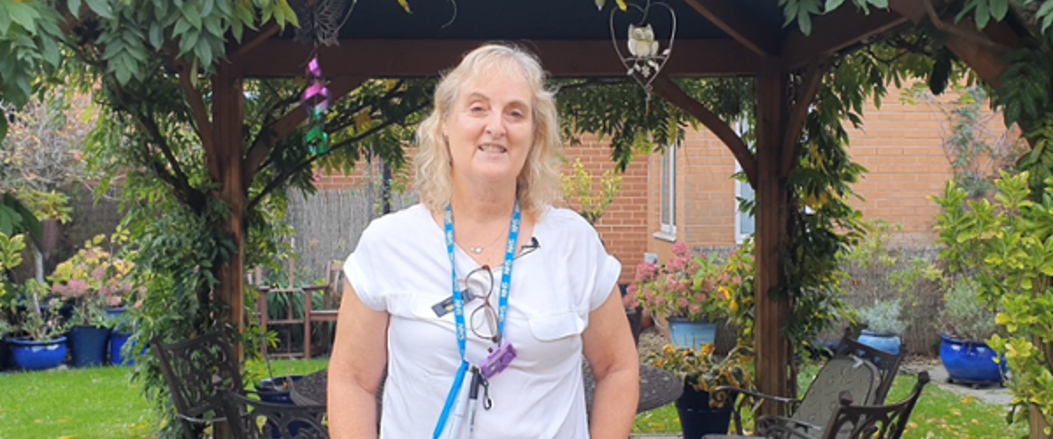 Dr Jane Mathlin is smiling in a garden at Velindre Cancer Centre.