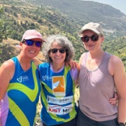 Three people are smiling side by side on a mountian.