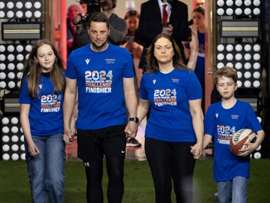 Craig Maxwell walking onto Principality Stadium pitch with wife and two children.