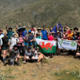 A large group of people are stood together on a mountian during a trek.