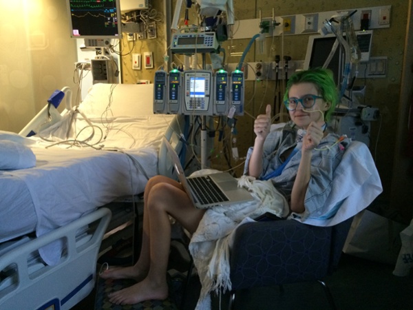 Emma is sat on a chair next to a bed during one of her hospital stays.