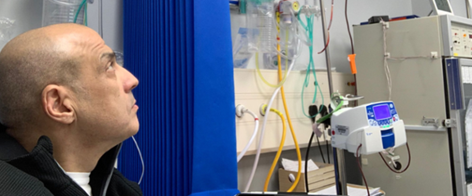 A patient is in a hospital room and looking towards various pieces of medical equipment.