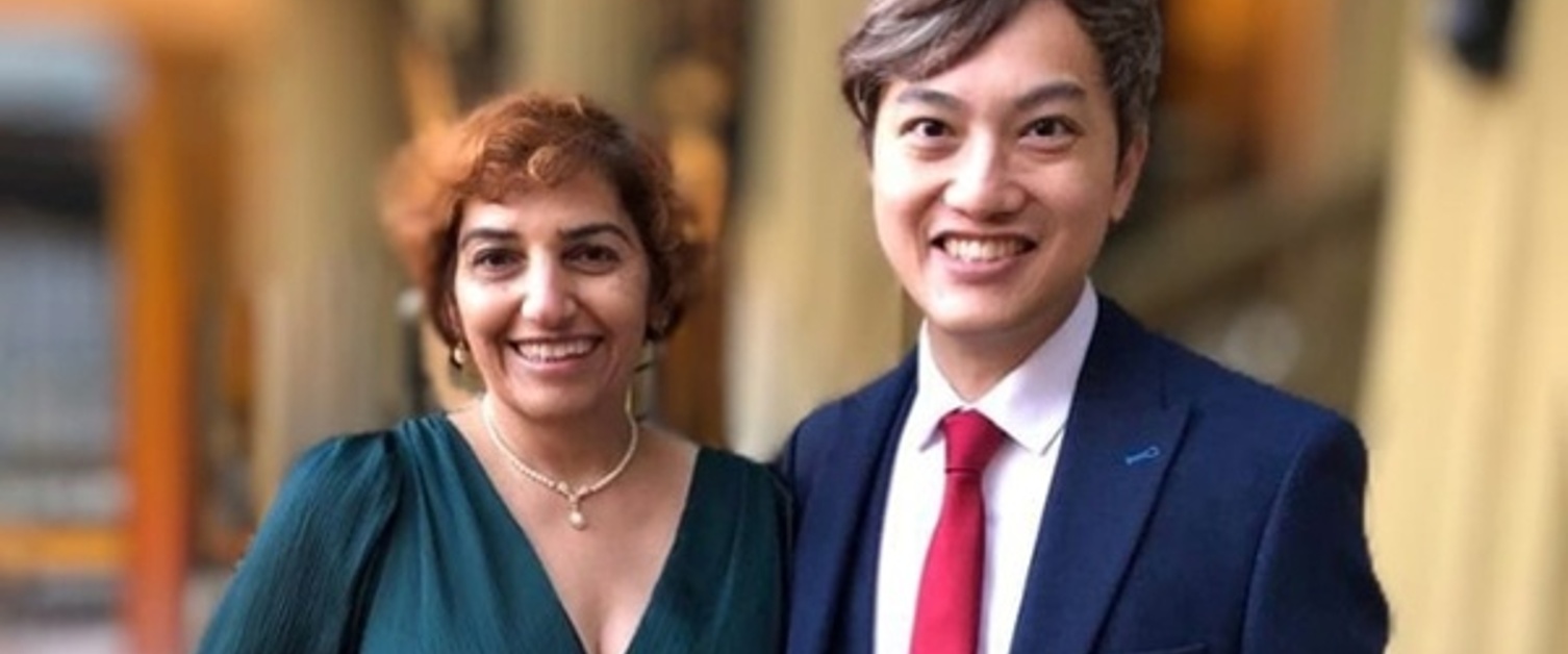 Two people are dressed smartly and smiling.