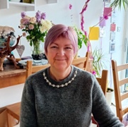 head and shoulders picture of Jane Henderson in her dining room with flowers behind her